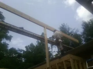 Carpenter setting a ridge beam over a new addition frame — Ice Dam Removal by Roofing Brothers in Cedar Lake
