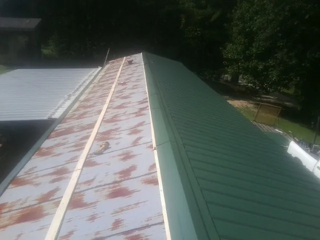 Old rusted panels beside newly installed green metal roofing — Wind Damage Roof Repair by Roofing Brothers in Cedar Lake