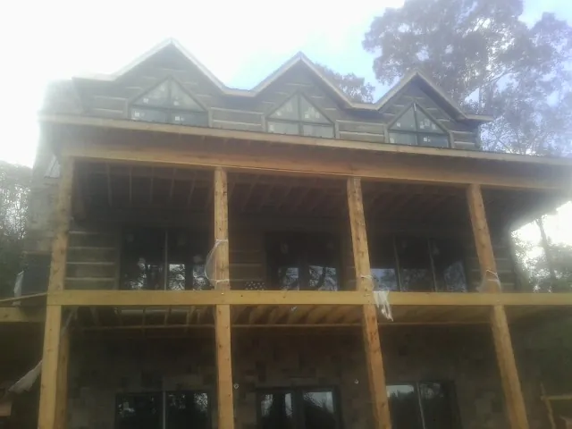 Dormers and porch framing on a large log home under construction — Roof Coating work by our crew in Cedar Lake