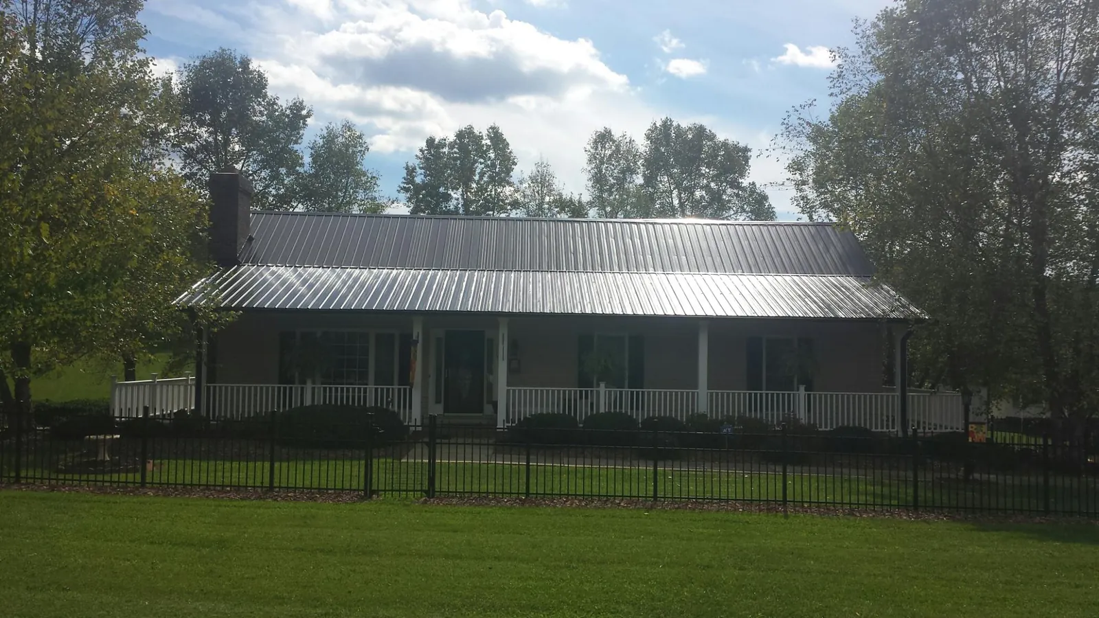 Gray metal roof on a brick ranch with a full width front porch — Gutter Guard Installation work by our crew in Cedar Lake