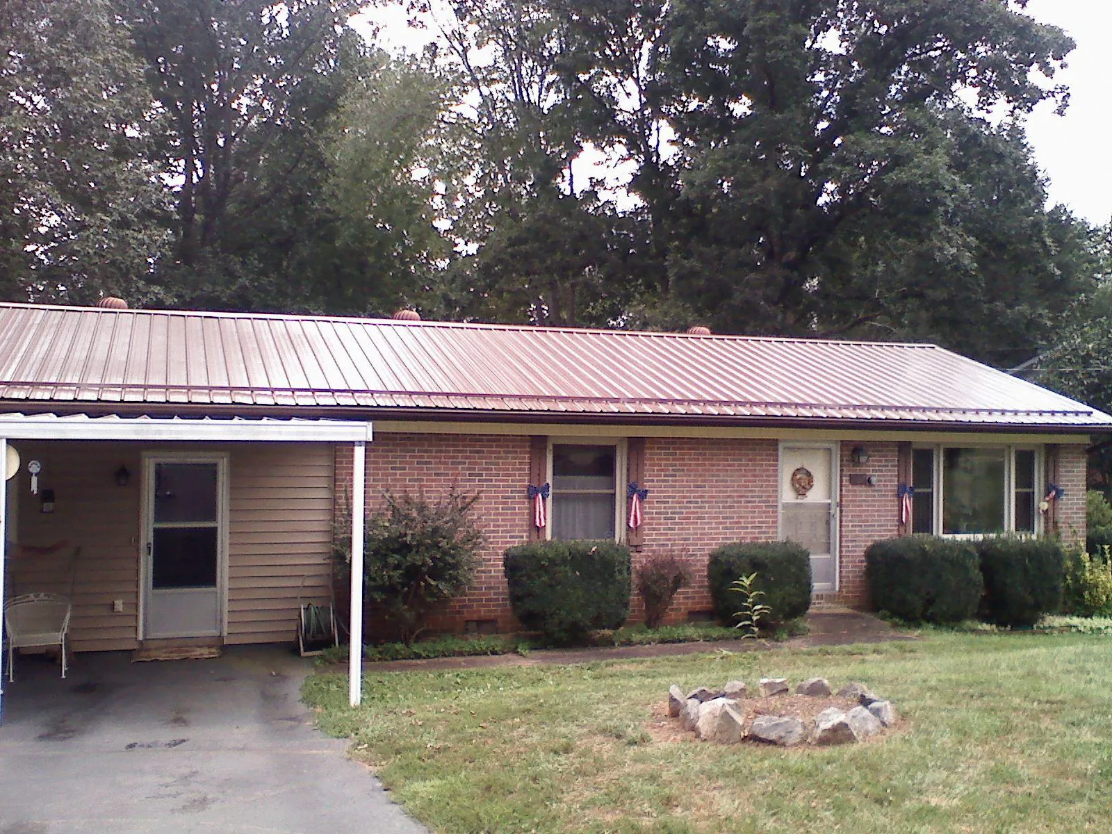 Bronze metal roof and carport on a brick ranch home — Roof Repair work by our crew in Cedar Lake