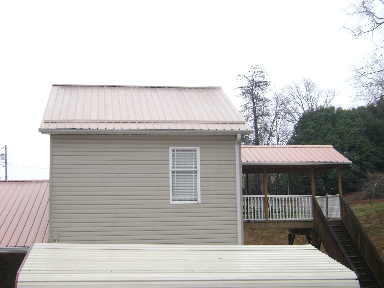 Tan metal roofs on a two story addition and attached porch, from a Roof Replacement job in Cedar Lake