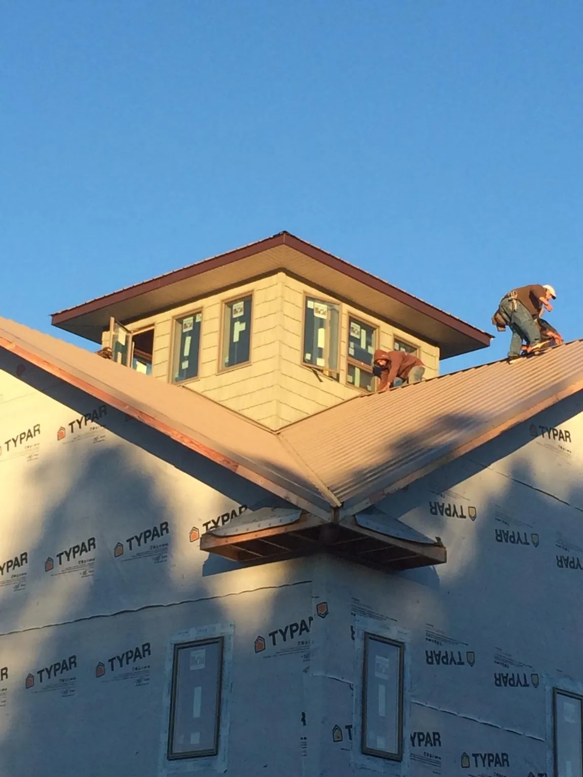 Roofers working around a rooftop cupola on a new metal roof at sunset — Roof Waterproofing in Cedar Lake by Roofing Brothers